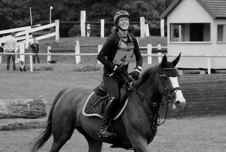 Kelly van Delft souriante à cheval, au pas après son parcours de cross en concours complet