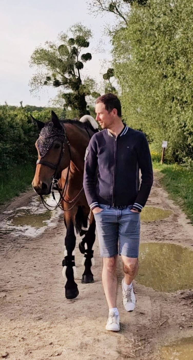 Marc-André van Delft marchant à côté d'un cheval bai dans un chemin